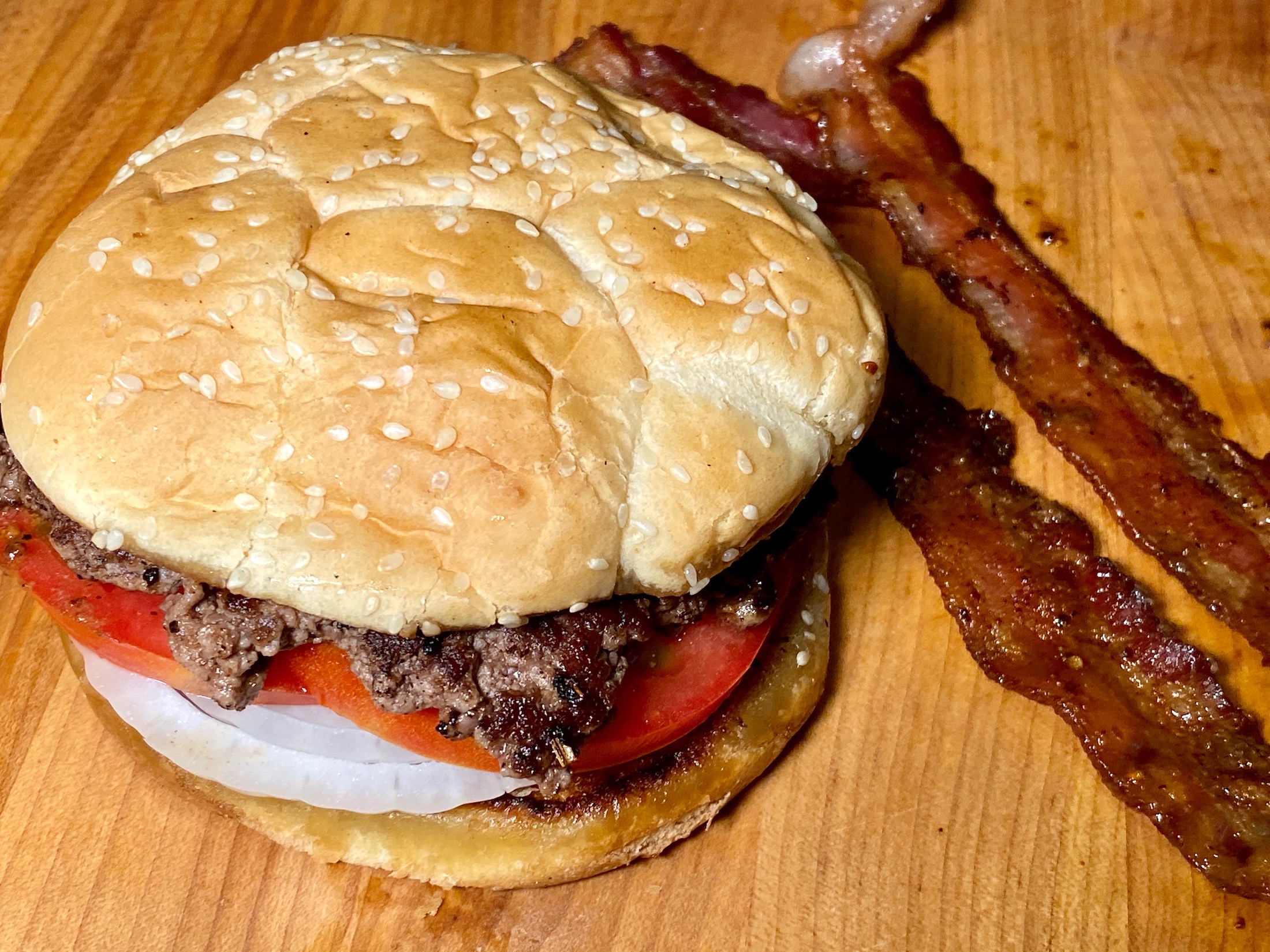 smash burger on bun with bacon on side