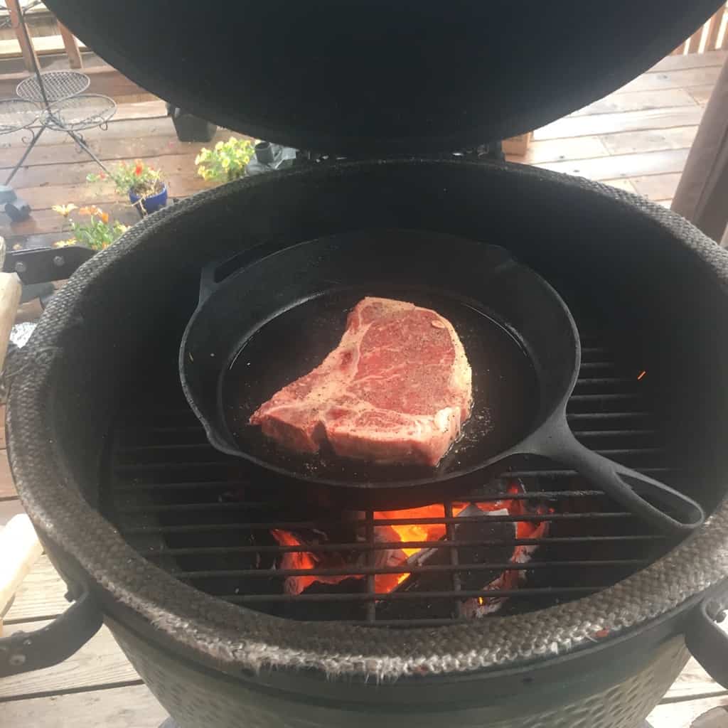 A steak cooking in cast iron on the grill