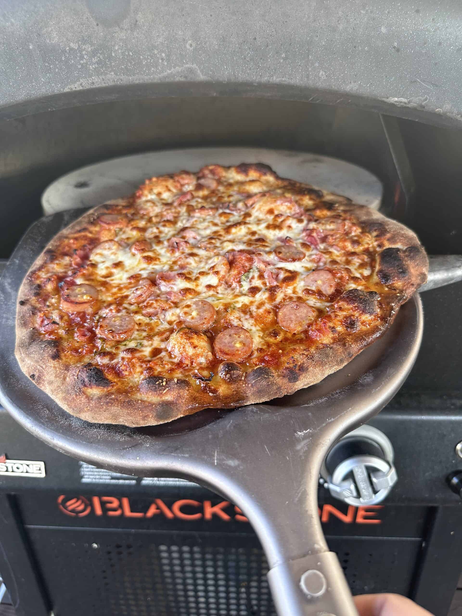 An Outdoor Pizza Oven with a pizza on a Peel